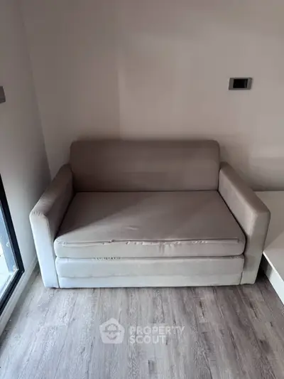 Cozy small sofa in a modern apartment with wooden flooring and neutral tones.