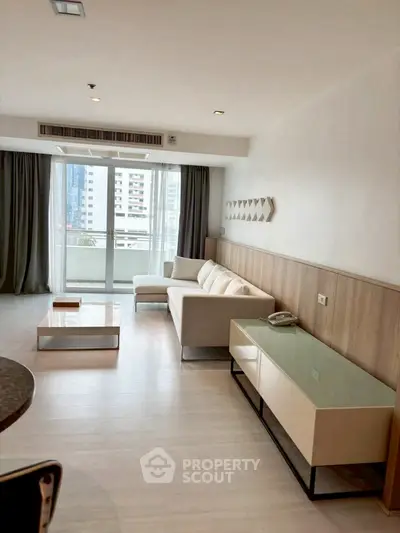 Modern living room with sleek furniture and large windows offering city views.