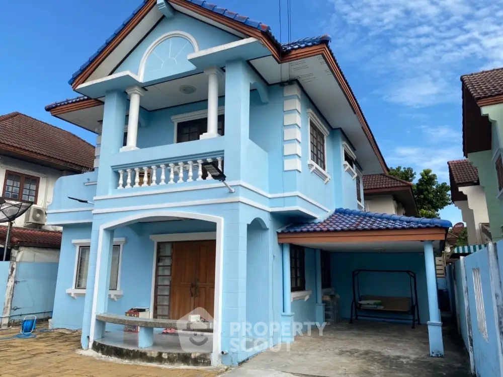 Charming blue two-story house with tiled roof and spacious driveway