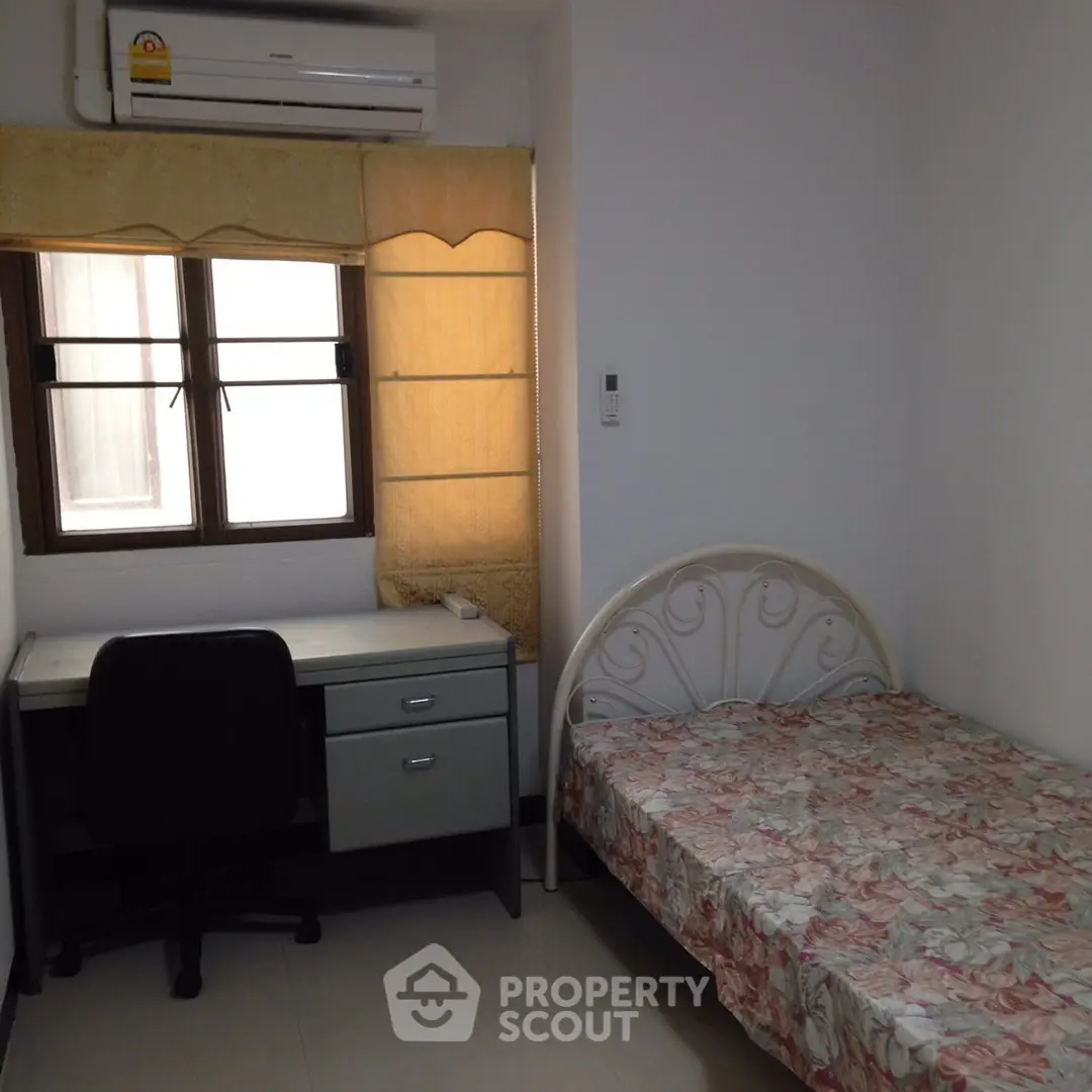 Cozy bedroom with single bed, desk, and air conditioning in a bright apartment.