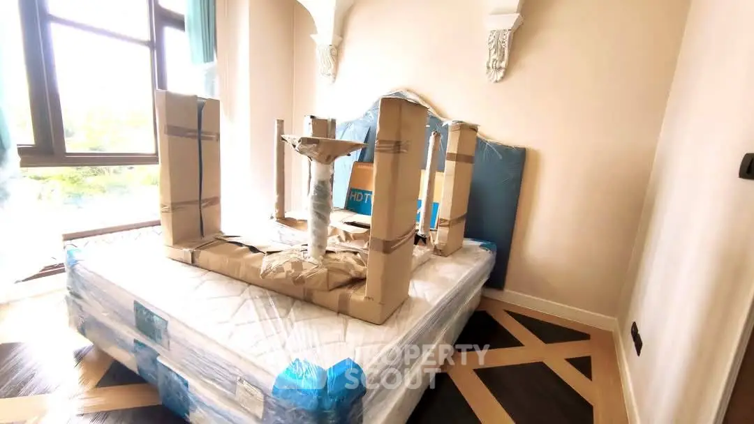 Spacious bedroom with large windows and new furniture being set up, offering potential for customization.