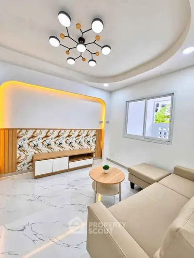 Modern living room with stylish lighting and marble accents, featuring a cozy beige sofa and sleek coffee table.