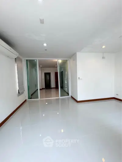 Spacious modern living room with glossy white tiles and sliding glass doors