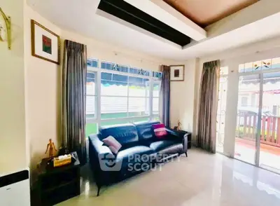 Spacious living room with modern black leather sofa and large windows for natural light.