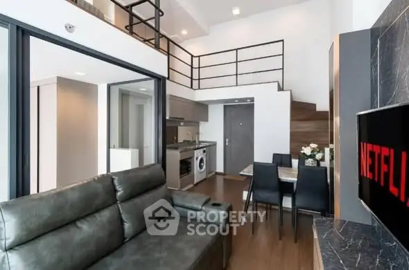 Modern loft apartment with open kitchen and stylish living area, featuring a mezzanine and sleek furnishings.