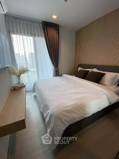 Modern bedroom with large window and stylish decor in a contemporary apartment.