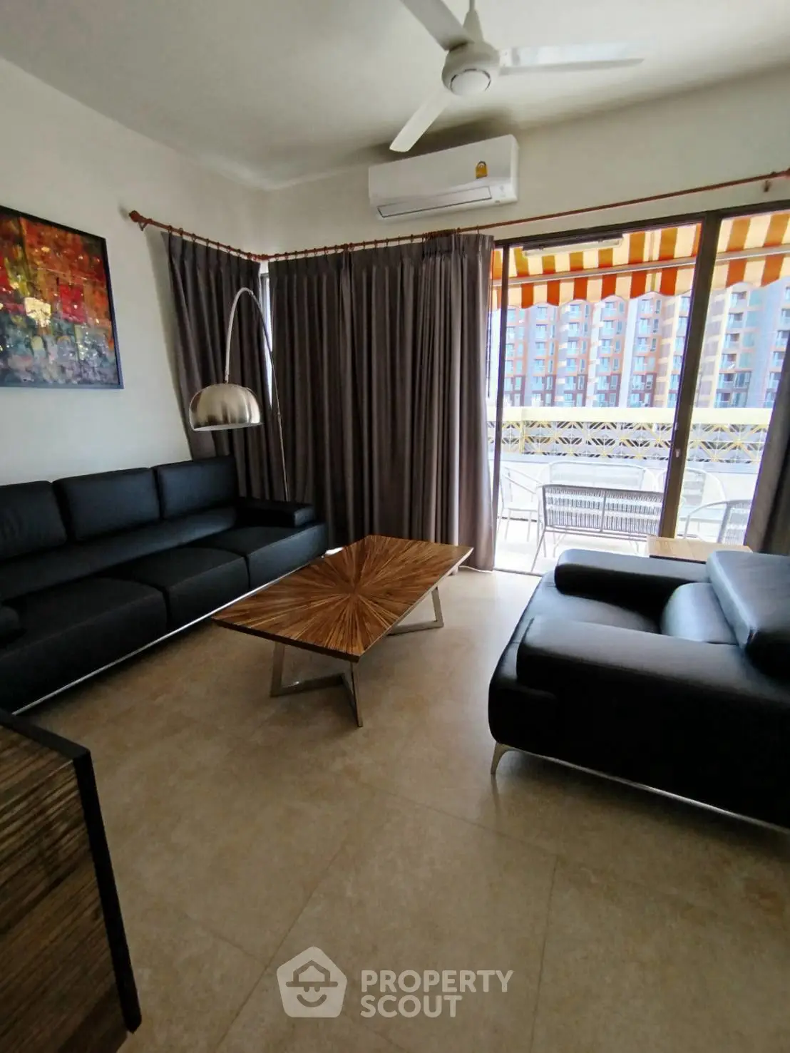 Modern living room with sleek black sofas, stylish coffee table, and balcony view in a contemporary apartment.