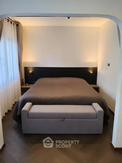 Elegant bedroom with modern decor and cozy lighting, featuring a stylish bed and seating area.
