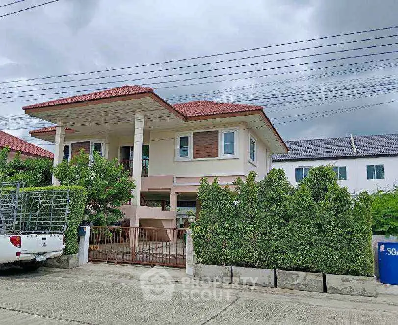 Charming two-story house with red roof and lush greenery in a serene neighborhood.