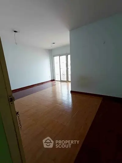 Spacious empty room with large windows and wooden flooring, ideal for customization.