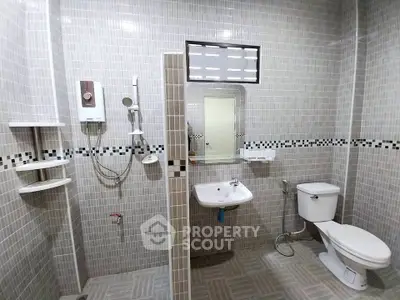 Spacious modern bathroom with tiled walls and essential fixtures, ideal for comfort and functionality.