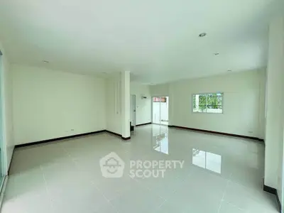 Spacious and bright living room with large windows and glossy tiled floors, perfect for modern living.