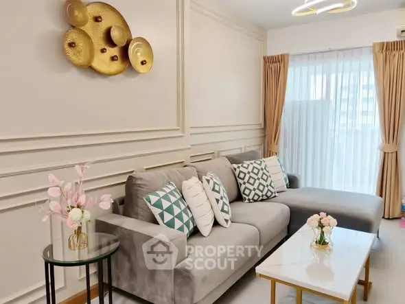 Elegant living room with modern decor and large window, featuring a stylish gray sofa and chic wall art.
