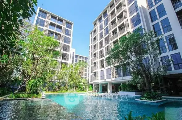Luxurious modern apartment complex with stunning pool and lush greenery.