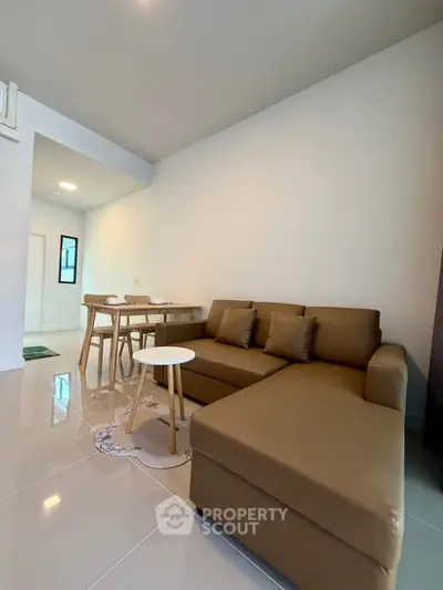 Modern living room with sleek brown sofa and dining area in open layout.