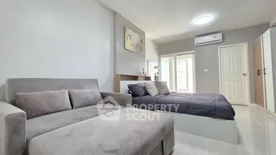 Modern bedroom with stylish decor and cozy seating area, featuring natural light and sleek furnishings.