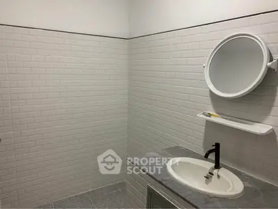Modern bathroom with sleek white tiles and stylish black faucet.