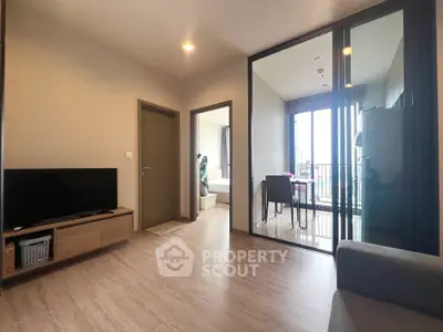 Modern living room with wooden flooring and glass partition leading to balcony