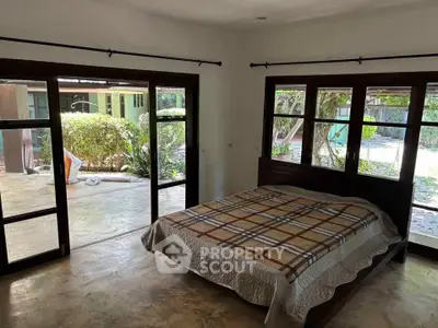 Spacious bedroom with large windows and garden view, featuring a cozy bed and natural light.