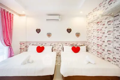 Charming bedroom with twin beds, heart-themed decor, and cozy ambiance for a perfect retreat.