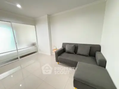 Modern minimalist living room with sleek gray sofa and glossy tiled floor