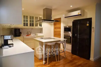 Modern kitchen with island, sleek appliances, and wooden flooring in a stylish home.