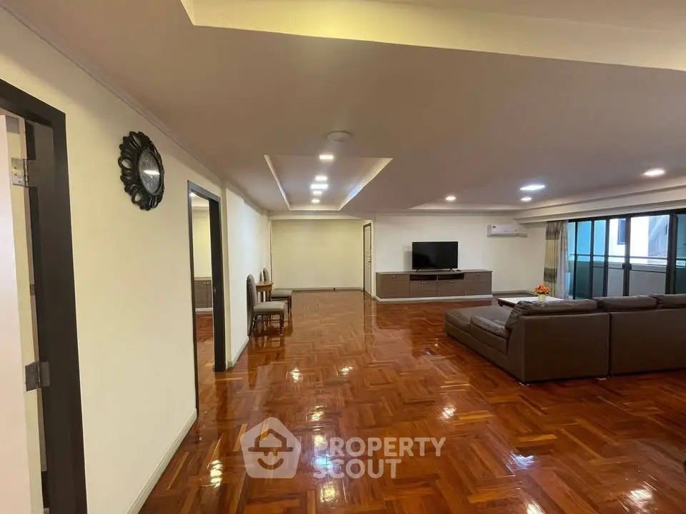 Spacious living room with polished wooden floors and modern furniture in a luxurious apartment.