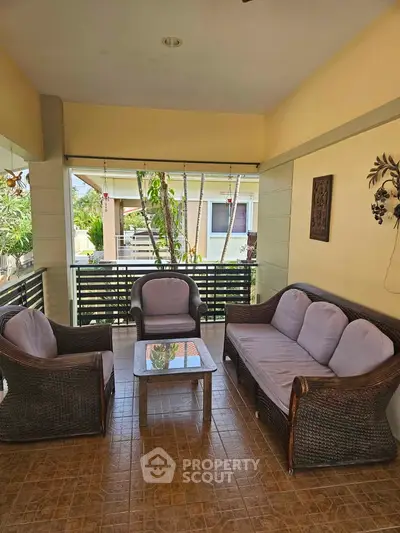 Charming balcony with cozy wicker furniture and garden view, perfect for relaxation.