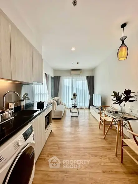 Modern open-plan living room with kitchen, featuring stylish decor and natural light.