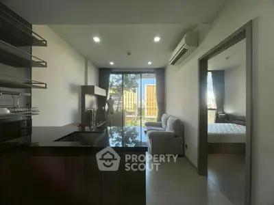 Modern apartment interior with open kitchen and cozy living area, featuring a balcony view.