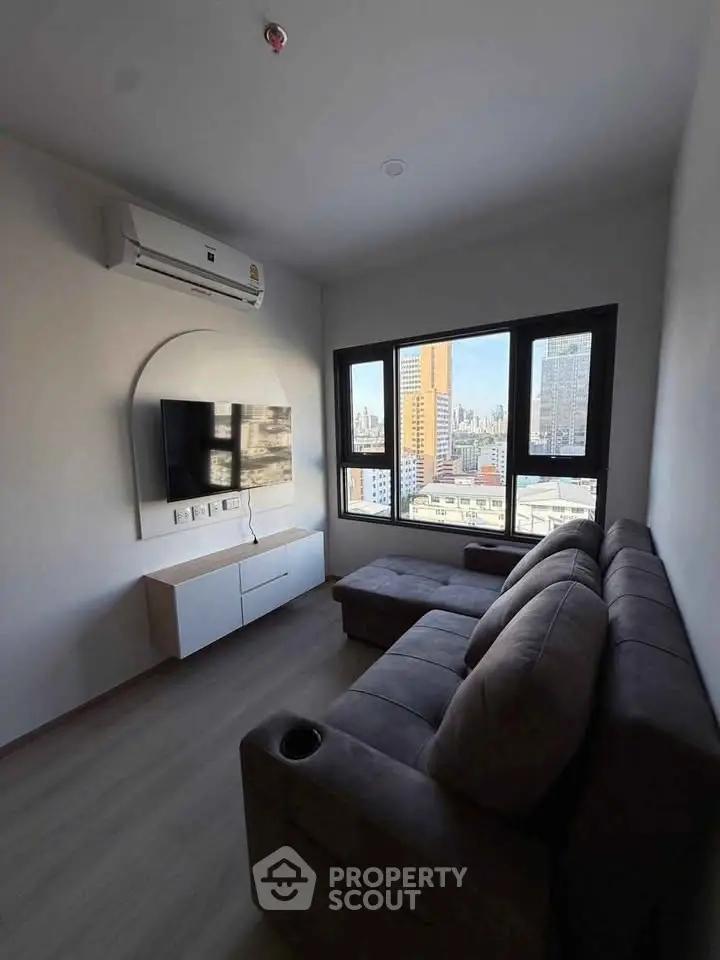 Modern living room with city view, featuring sleek furniture and large windows.