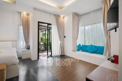 Spacious modern bedroom with large windows and garden view, featuring elegant decor and natural light.