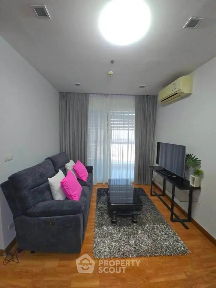 Modern living room with cozy sofa, stylish decor, and natural light through large window.