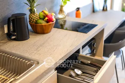 Modern kitchen with sleek countertop, built-in stove, and organized cutlery drawer.