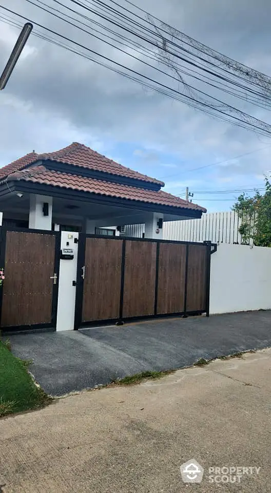 Charming single-story home with tiled roof and gated entrance in serene neighborhood.