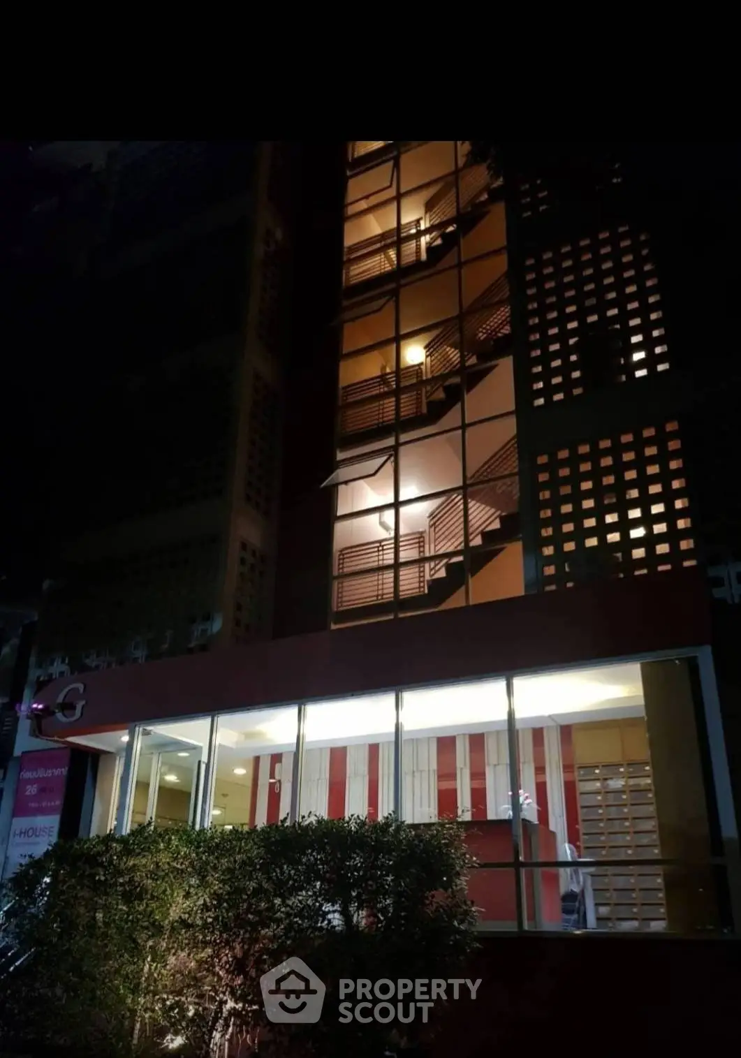 Modern building exterior with illuminated stairwell and glass facade at night.