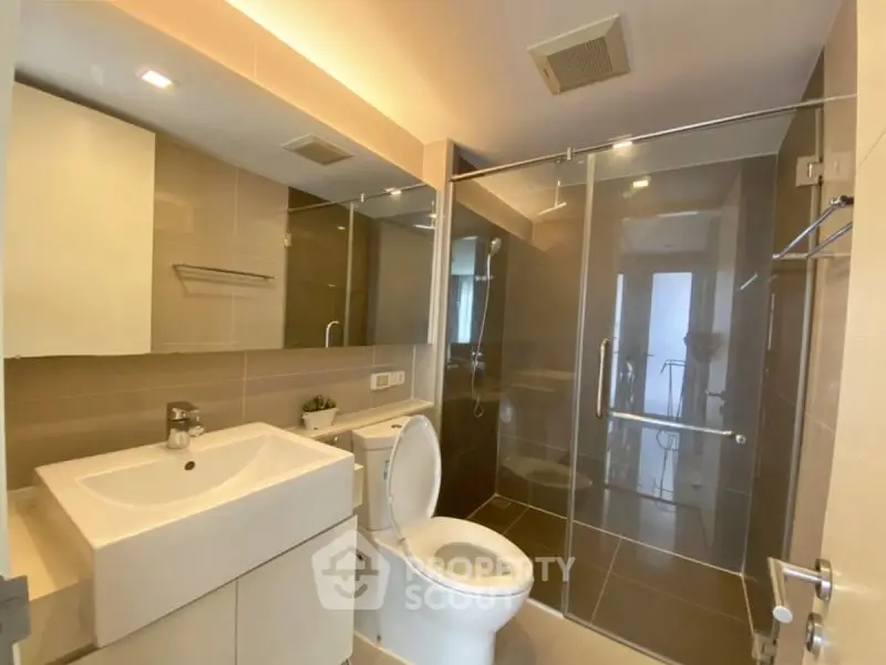 Modern bathroom with glass shower and sleek fixtures in a contemporary apartment.