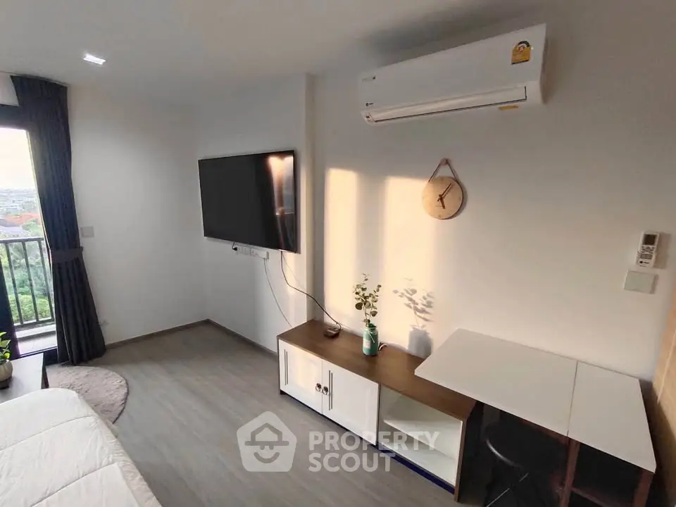 Modern living room with wall-mounted TV and air conditioning, featuring a balcony view.