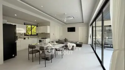 Modern open-plan living room and kitchen with large windows and stylish decor