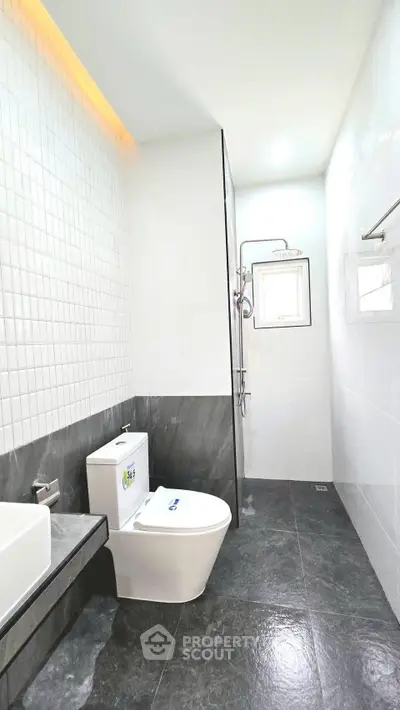 Modern bathroom with sleek design, featuring a stylish toilet and shower area, perfect for contemporary living.