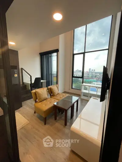 Modern living room with high ceiling and city view, featuring stylish furniture and large windows.