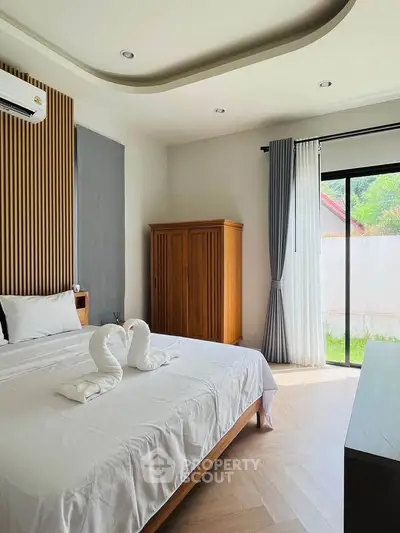 Elegant bedroom with modern decor and garden view, featuring stylish wooden furniture and natural light.