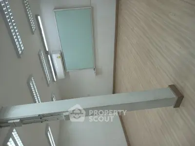 Spacious empty room with wooden flooring and bright lighting, ideal for office or studio setup.