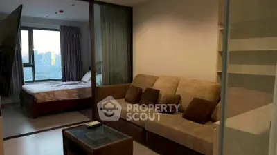 Modern apartment with cozy living room and bedroom, featuring a large window with city view.