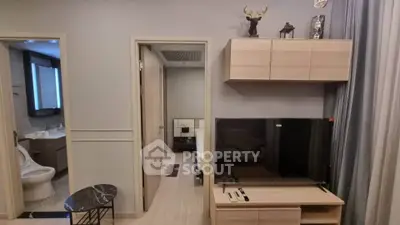 Modern living room with TV and stylish decor adjacent to bathroom and bedroom.