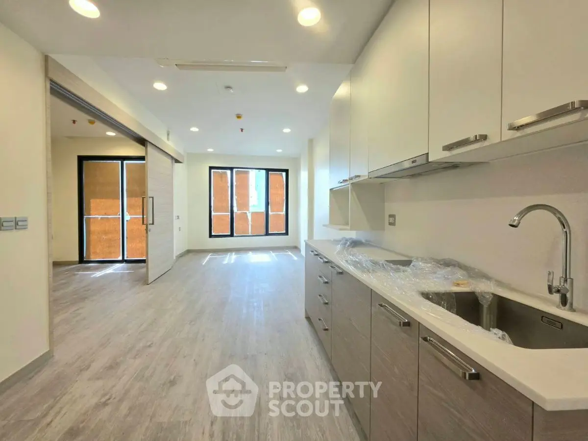 Modern kitchen with sleek cabinets and open layout leading to bright living area.