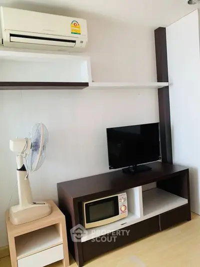 Modern living room with air conditioner, TV, and microwave on stylish furniture.