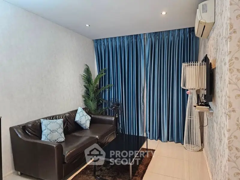 Modern living room with stylish decor and blue curtains, featuring a cozy leather sofa and wall-mounted TV.