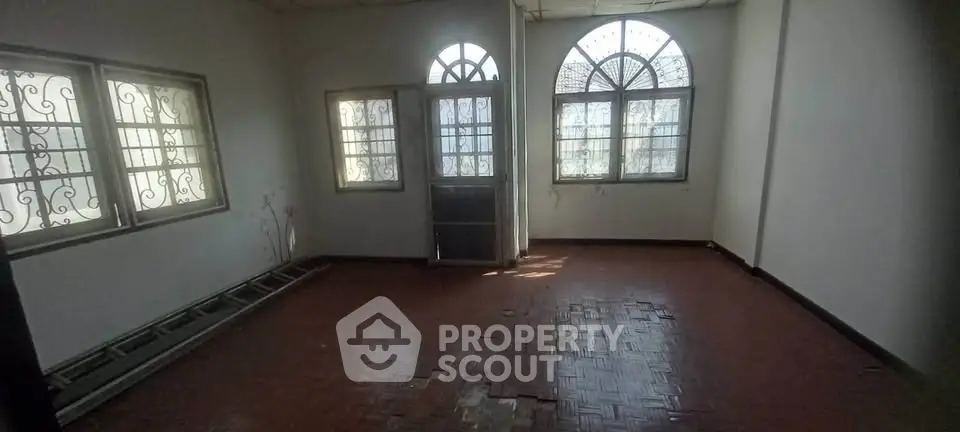 Spacious room with arched windows and tiled floor, ideal for customization.