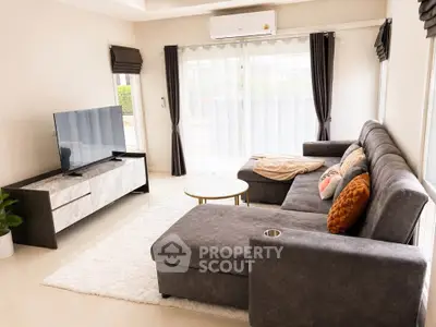 Spacious modern living room with plush gray sectional sofa and large TV, perfect for relaxation.
